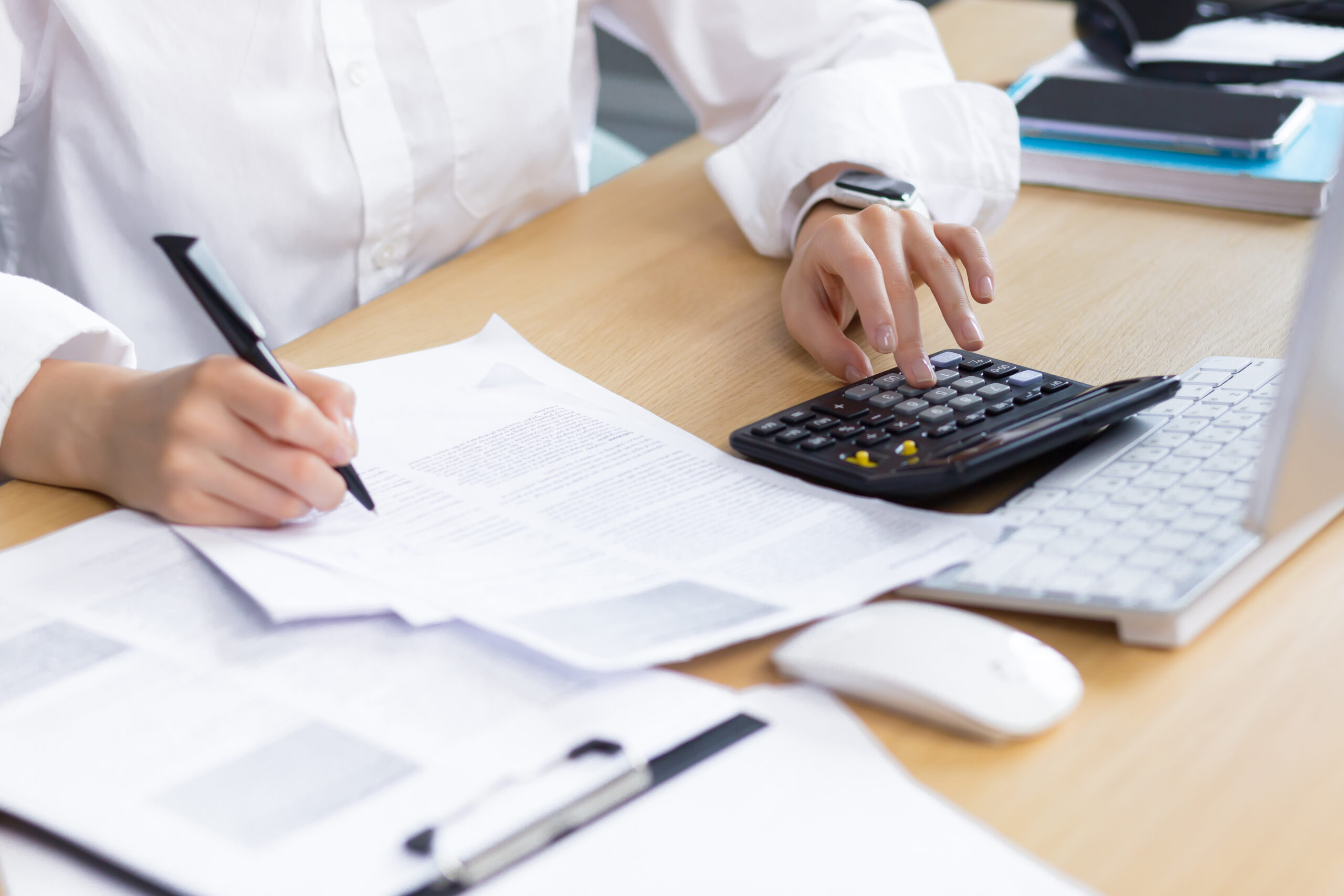 Close-up photo of a business woman's hand on paper work, an accountant calculates and summarizes the results of the financial year with a calculator, an Asian woman works in the office.
